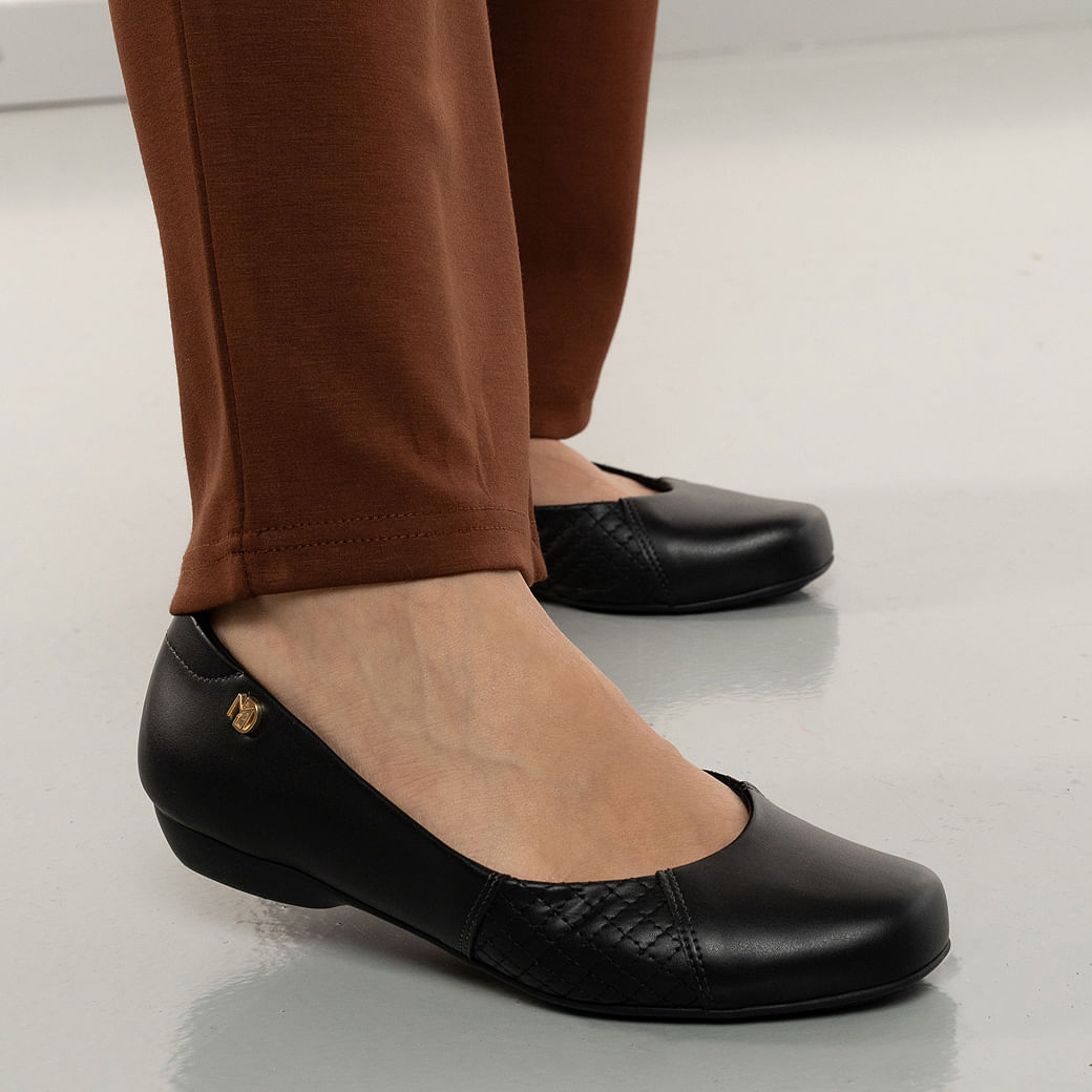 Sapatilha feminina preta Modare em material sintético com bico quadrado levemente arredondado, painel matelassê e detalhe metálico dourado